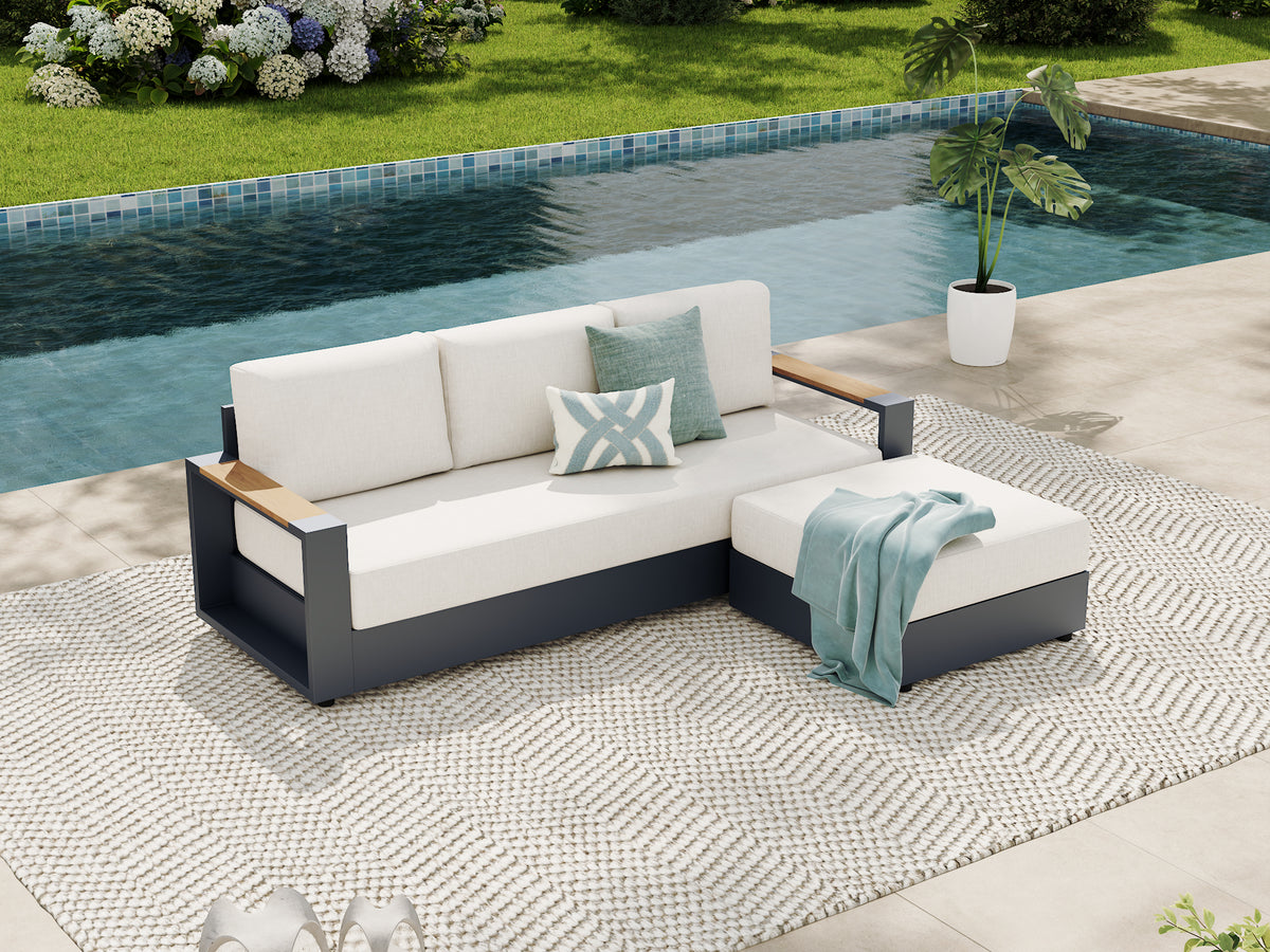 Outdoor sectional sofa with white cushions and a dark gray frame, styled on a patterned rug beside a swimming pool with decorative pillows and a throw blanket. #config_3-Seat Chaise
