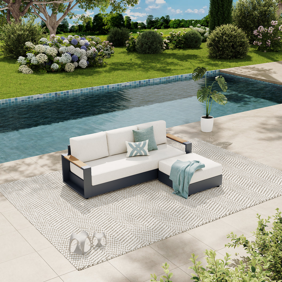Outdoor sectional sofa with white cushions and a dark gray frame, styled on a patterned rug beside a swimming pool in a landscaped garden setting. #config_3-Seat Chaise