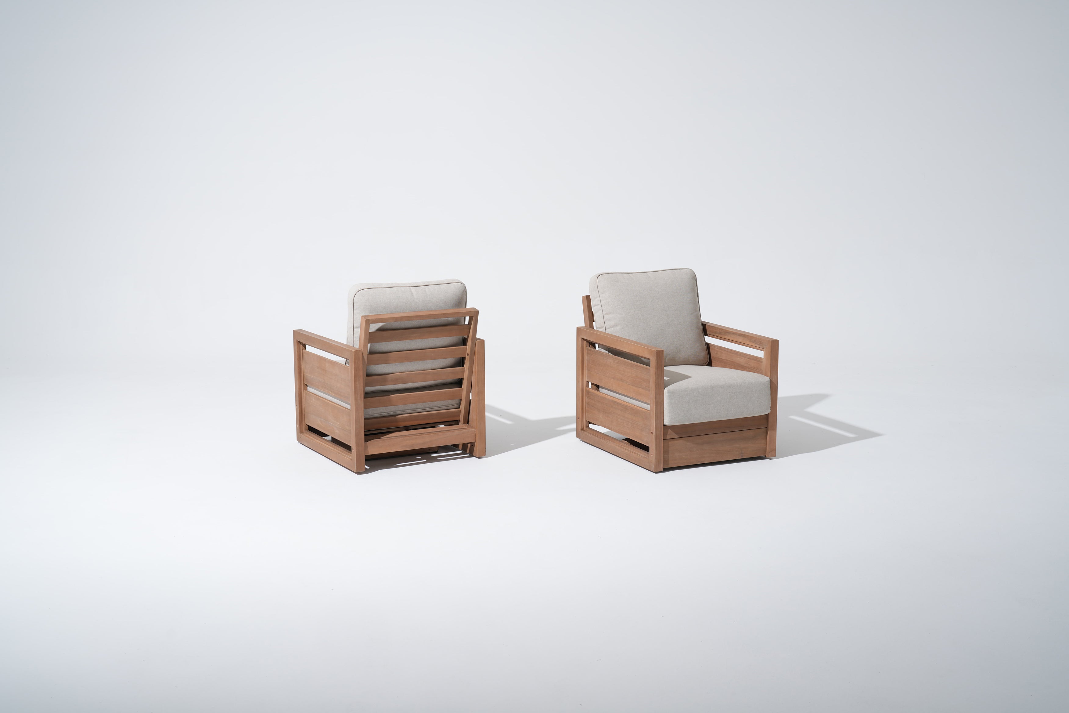 Two acacia wooden swivel chairs with beige cushions