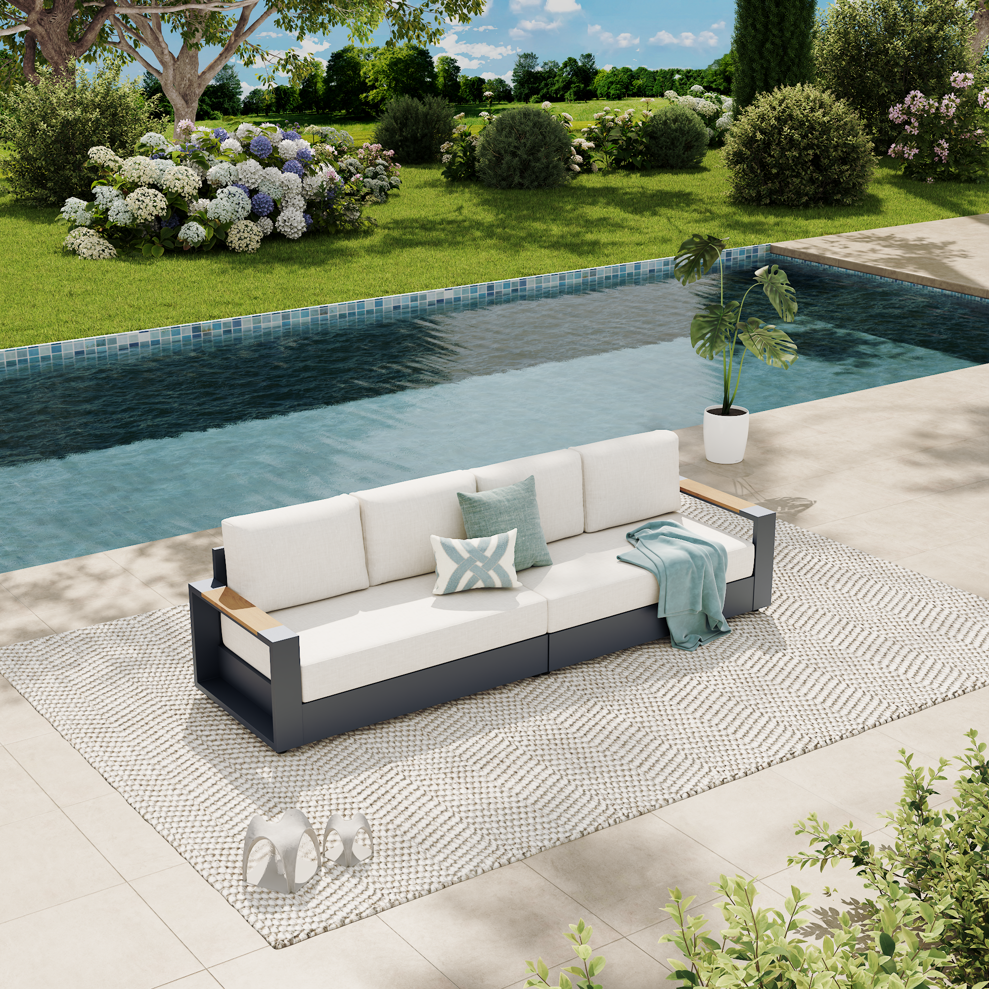 A modern outdoor sofa with white cushions and a dark gray frame sits on a patterned rug beside a swimming pool in a landscaped garden setting. #config_4‑Seat Straight