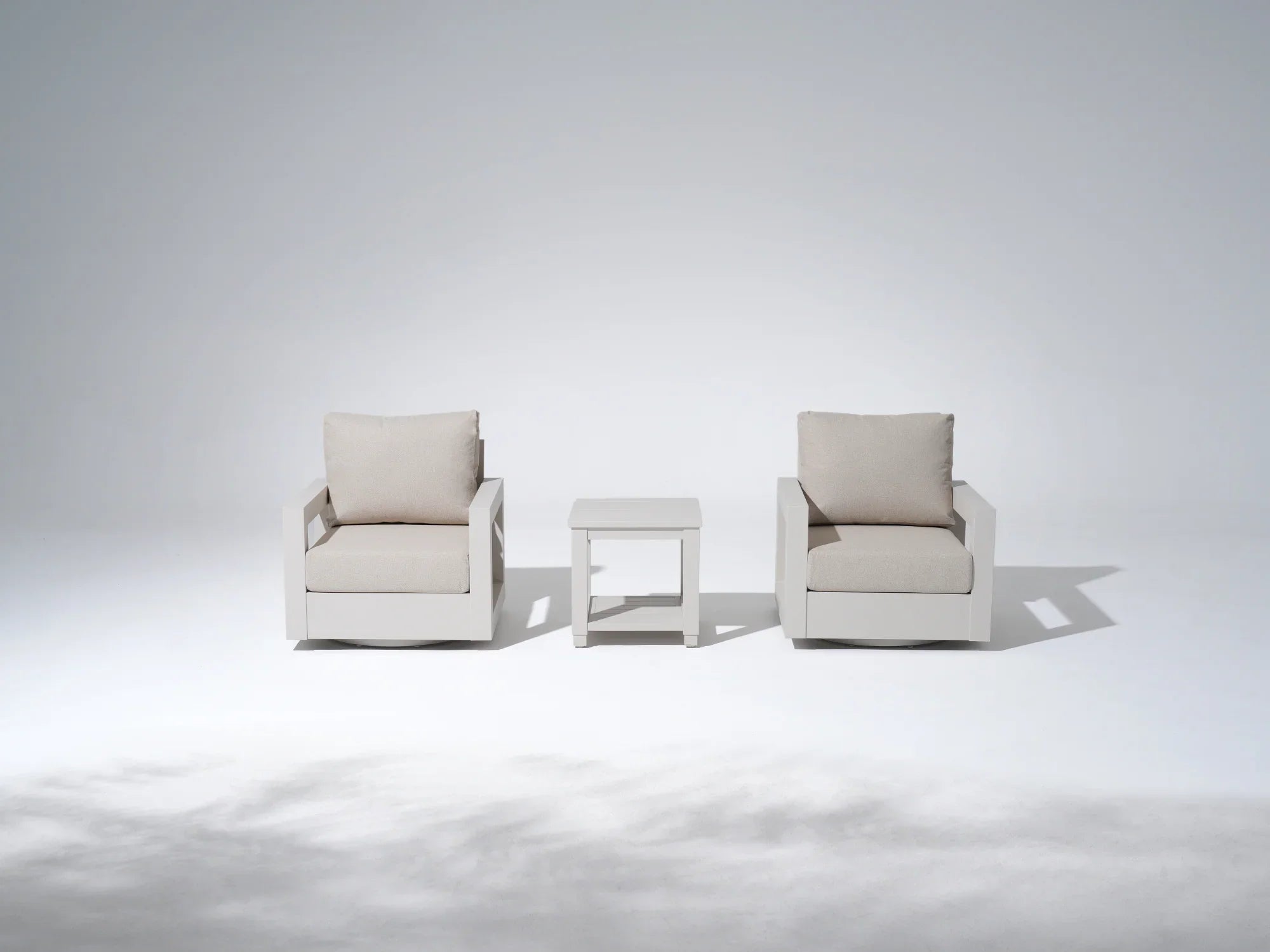 Two beige white aluminum swivel armchairs with cushions and a matching side table