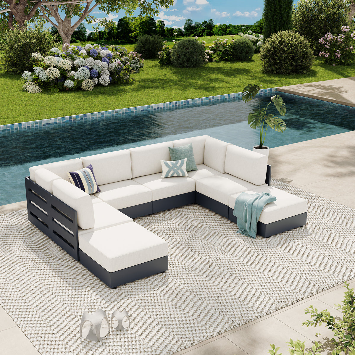An outdoor sectional sofa set with white cushions and a dark gray frame, arranged on a patterned rug beside a swimming pool in a landscaped garden. #config_U‑Shape with Ottomans