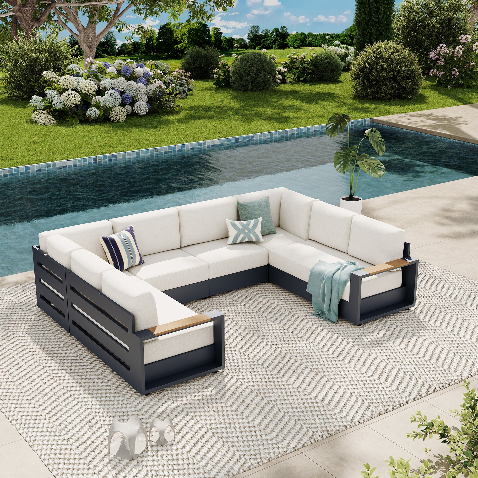 An outdoor sectional sofa with white cushions and a dark gray frame, arranged on a patterned rug beside a swimming pool in a landscaped garden setting. #config_8-Seat U‑Shape