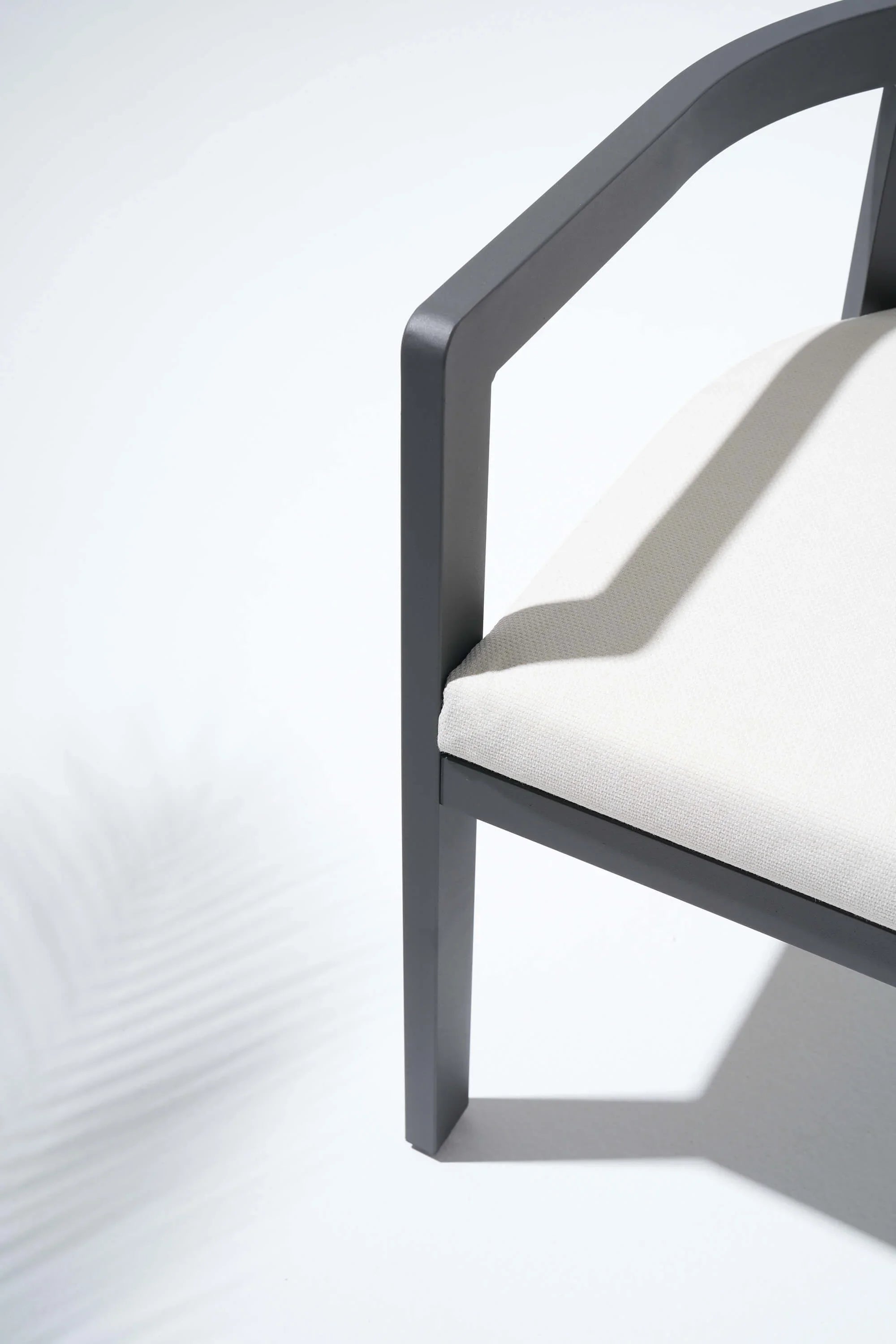 Close-up of a chair with a white cushion and curved armrest