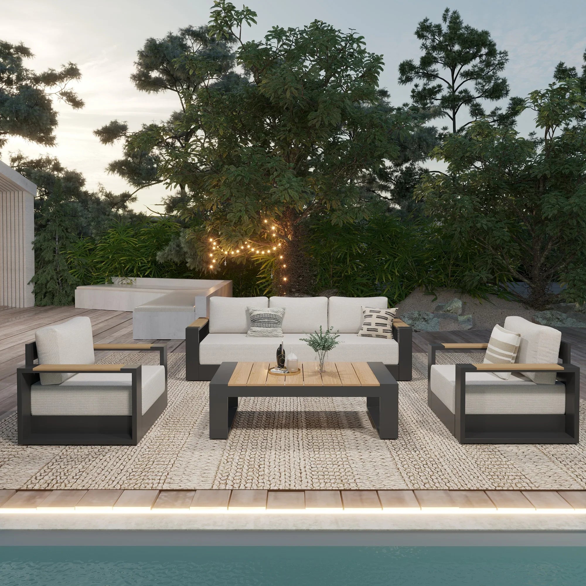 Outdoor patio furniture set with white cushions on a wooden deck by a pool.