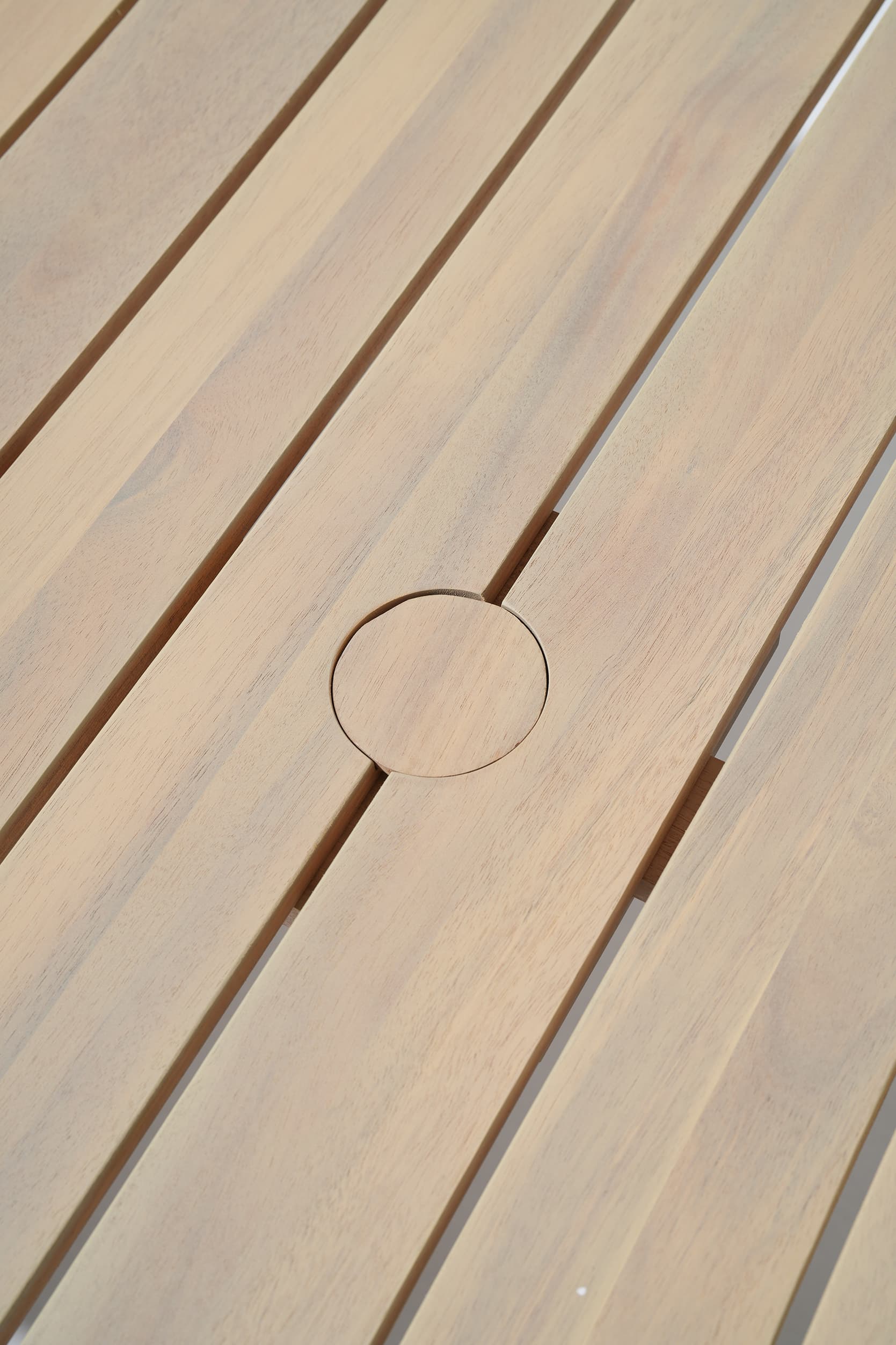 Close-up of acacia wooden slats table with a circular hole