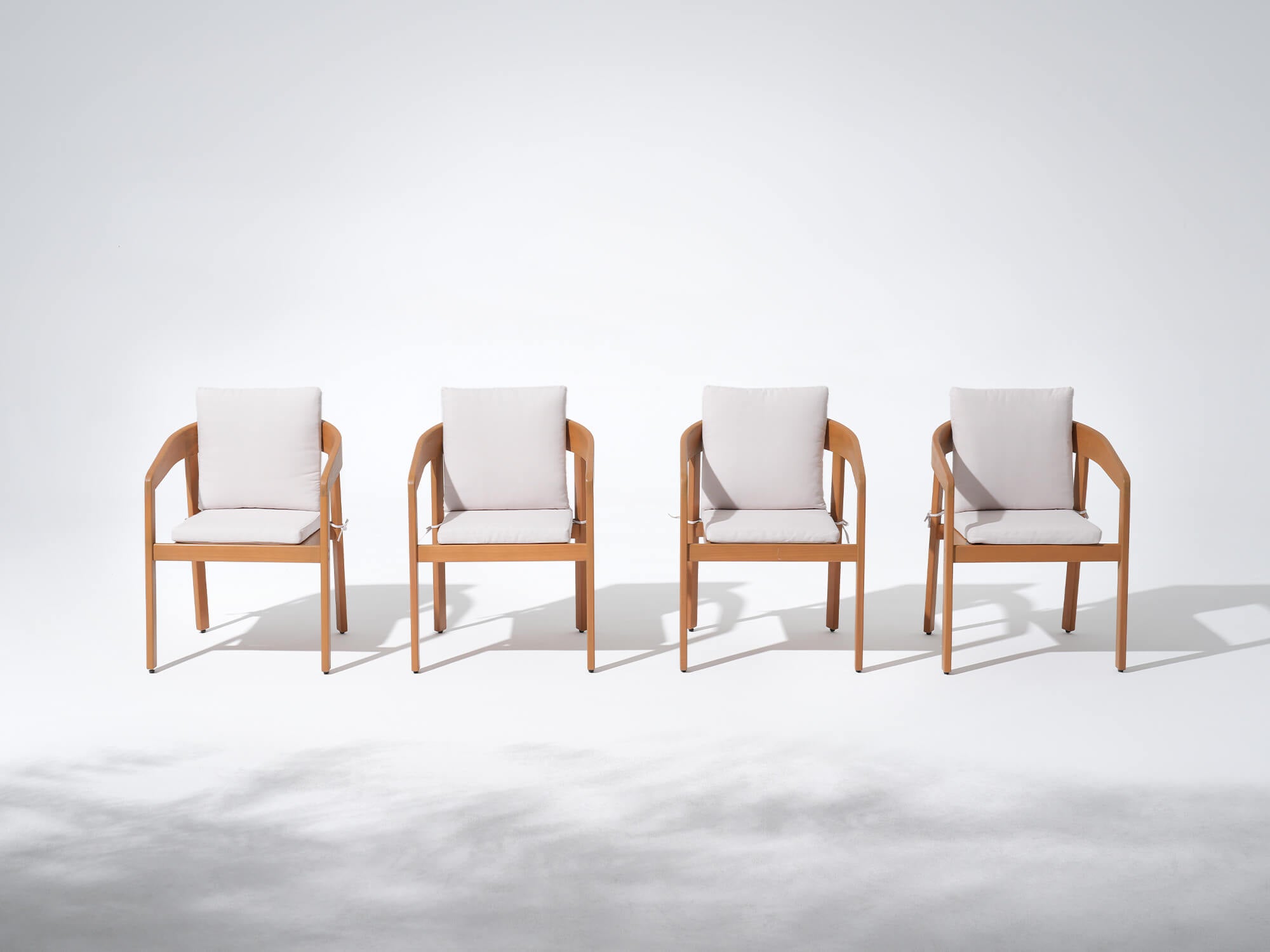 Four wooden dining chairs with white cushions on a white background - Jardina’s Modern Premium Outdoor Furniture