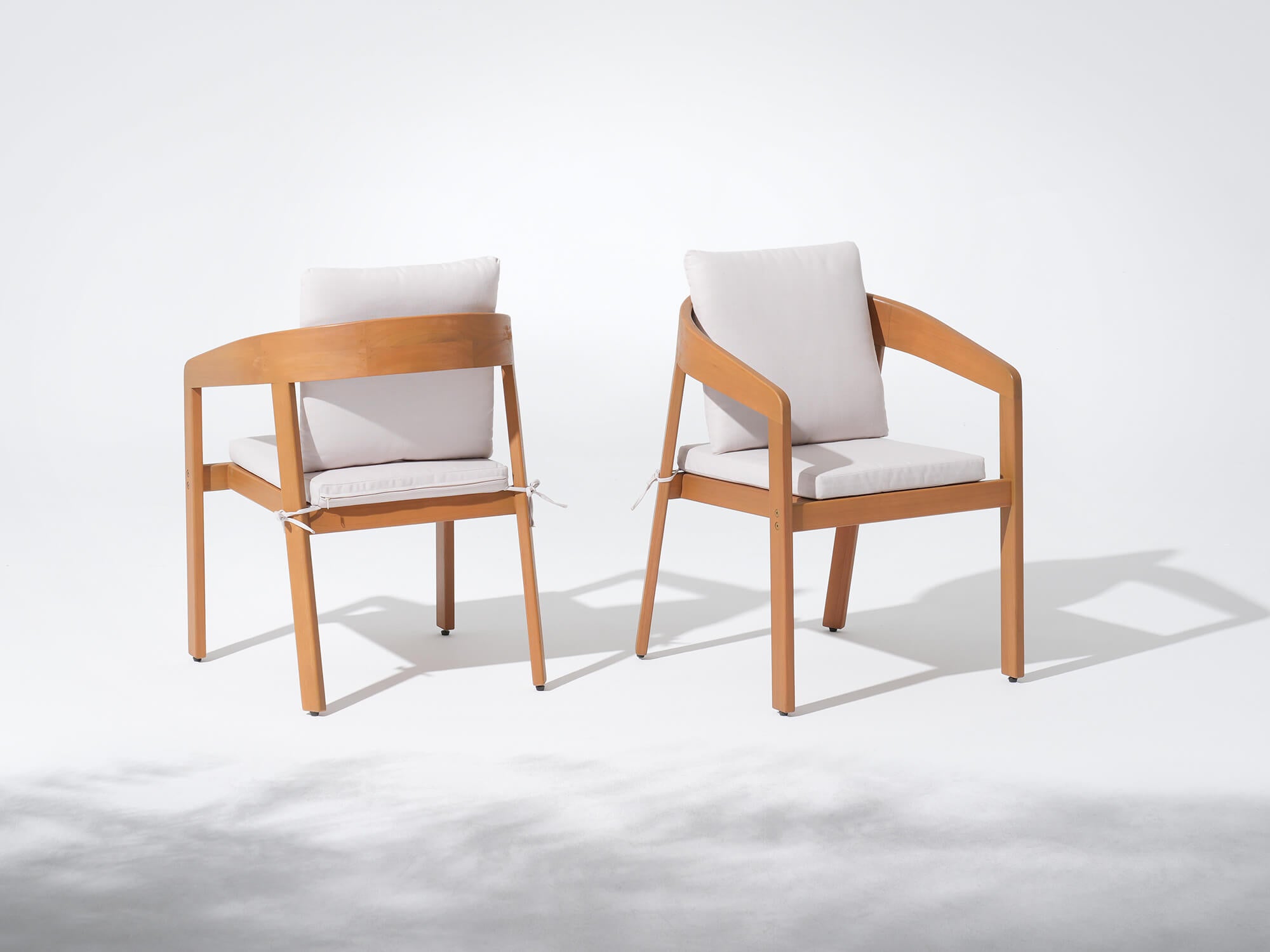 Two wooden chairs with white cushions on a white background, Drift Wooden Outdoor Dining Chairs With Curved Backrest - Jardina’s Modern Premium Outdoor Furniture