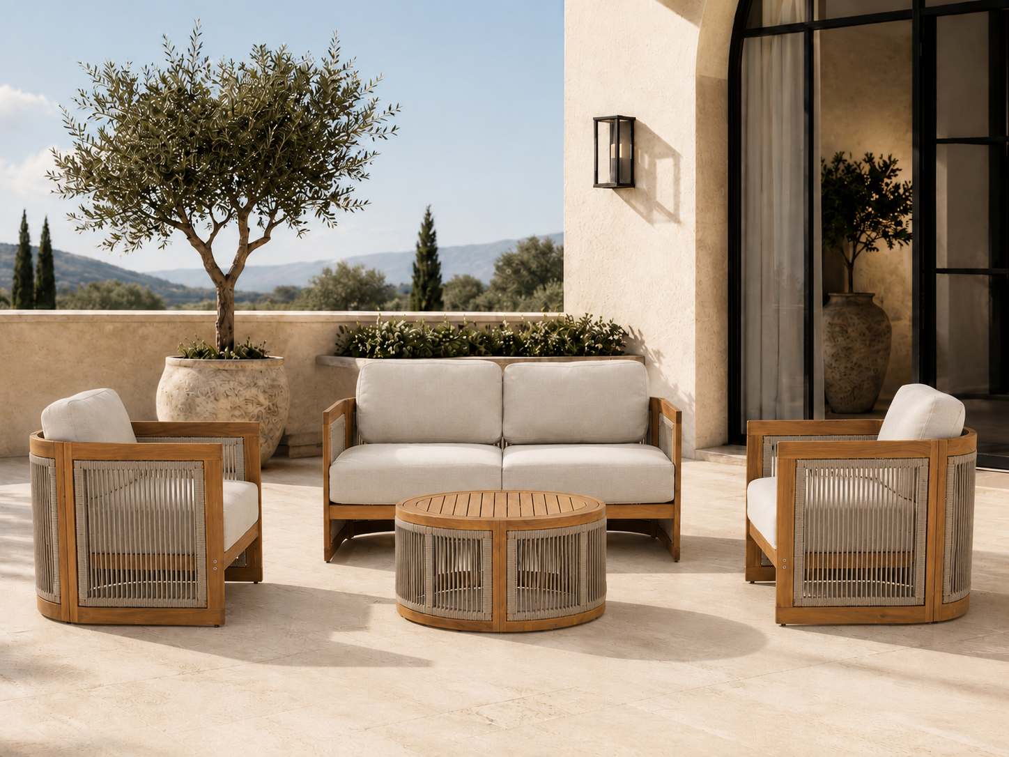 A 4-piece outdoor patio conversation set featuring a two-seater sofa, two armchairs, and a round coffee table, all in a warm light wood frame with beige rope details and off-white cushions, set on a stone patio with a stucco wall and a large potted tree in the background. #Size_4-pc with Loveseat
