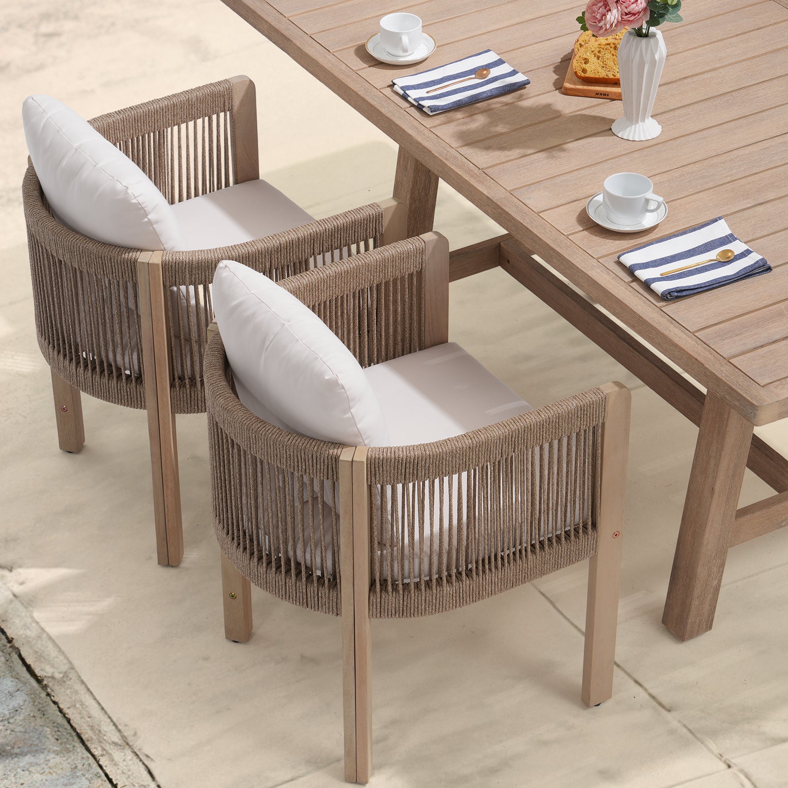 Two rope designed chairs with wooden frame and white cushions in front of a wooden dining table on a patio- Jardina Modern Premium Outdoor Patio Furniture