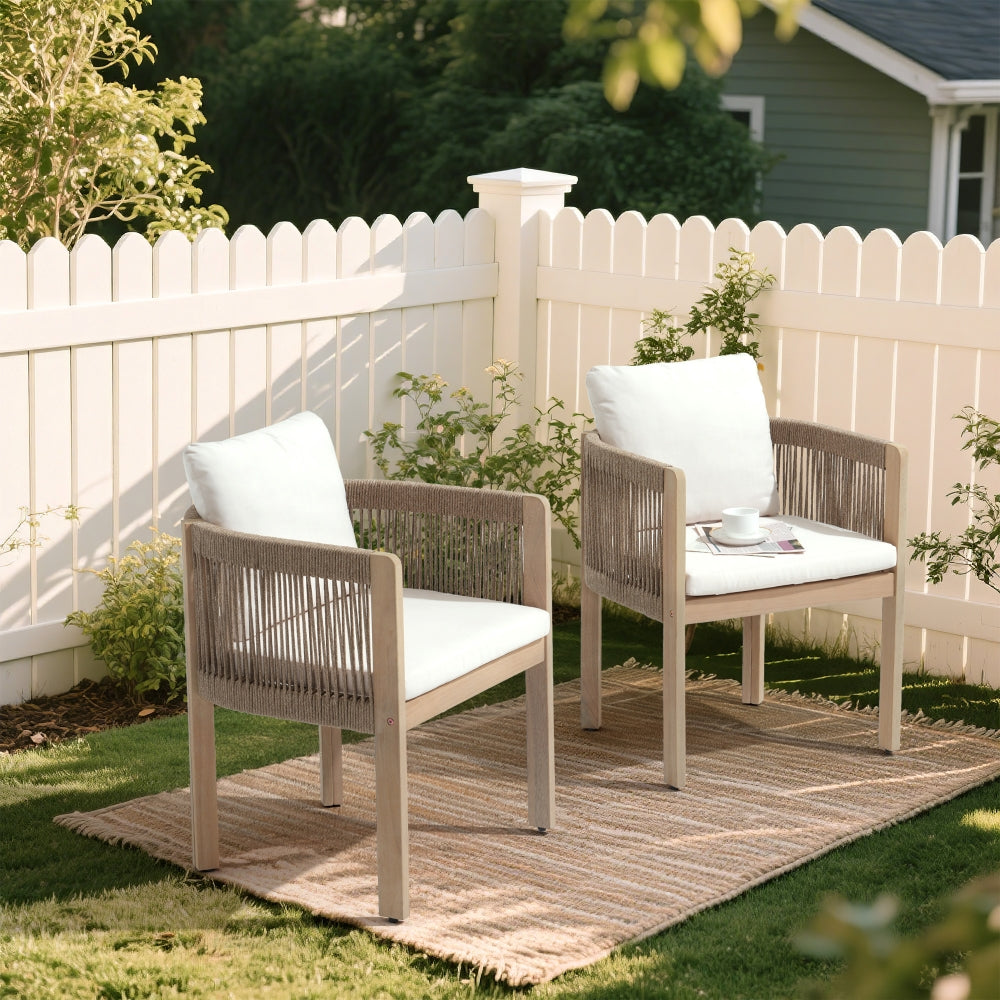 Two outdoor chairs with white cushions on a grassy area with a white picket fence in the background- Jardina Modern Premium Outdoor Patio Furniture