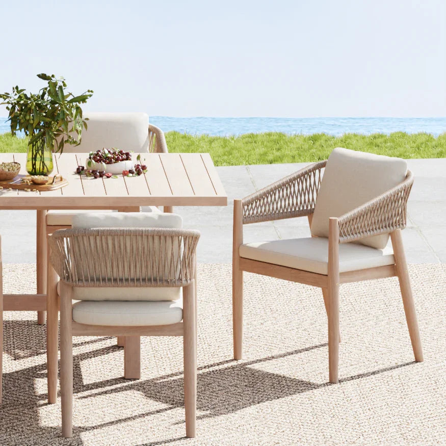 acacia wood Outdoor dining table with chairs on a pebble beach with ocean view