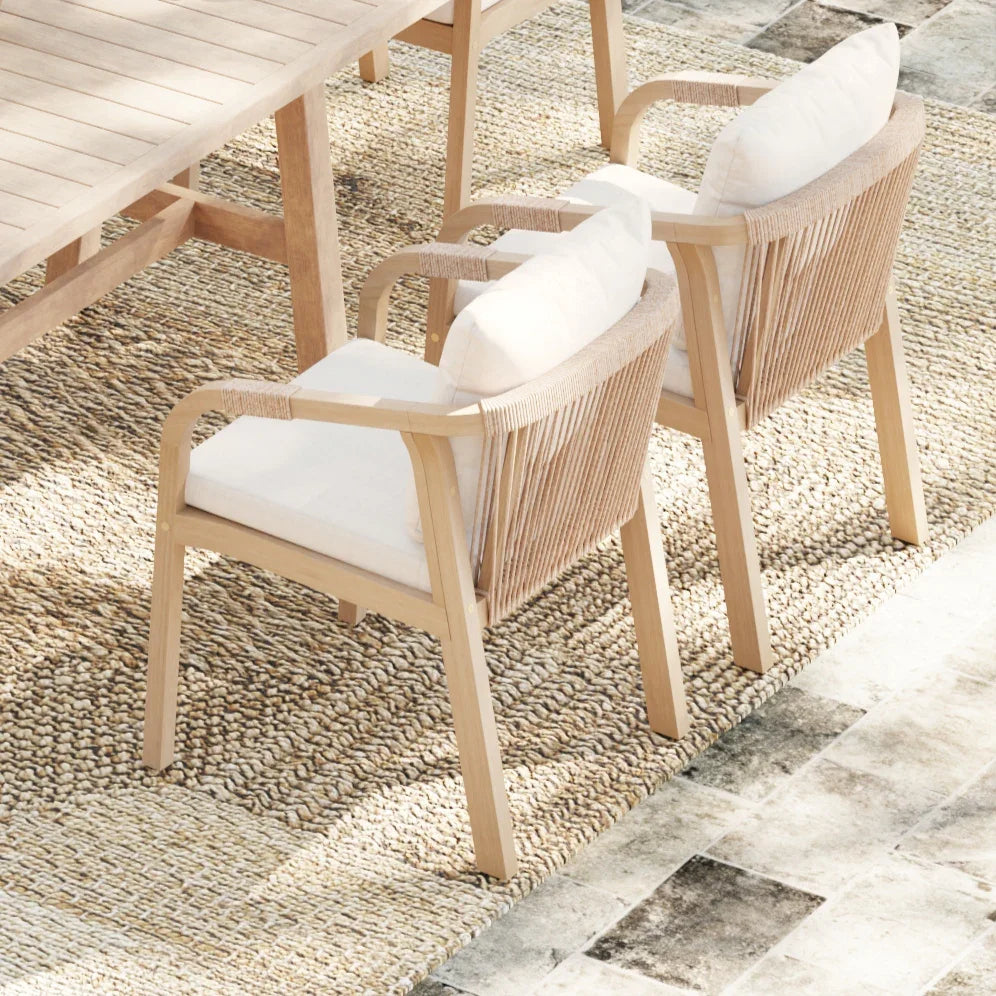 Wicker chair with white cushion on a textured stone floor - Jardina Premium Modern Outdoor Dining Furniture