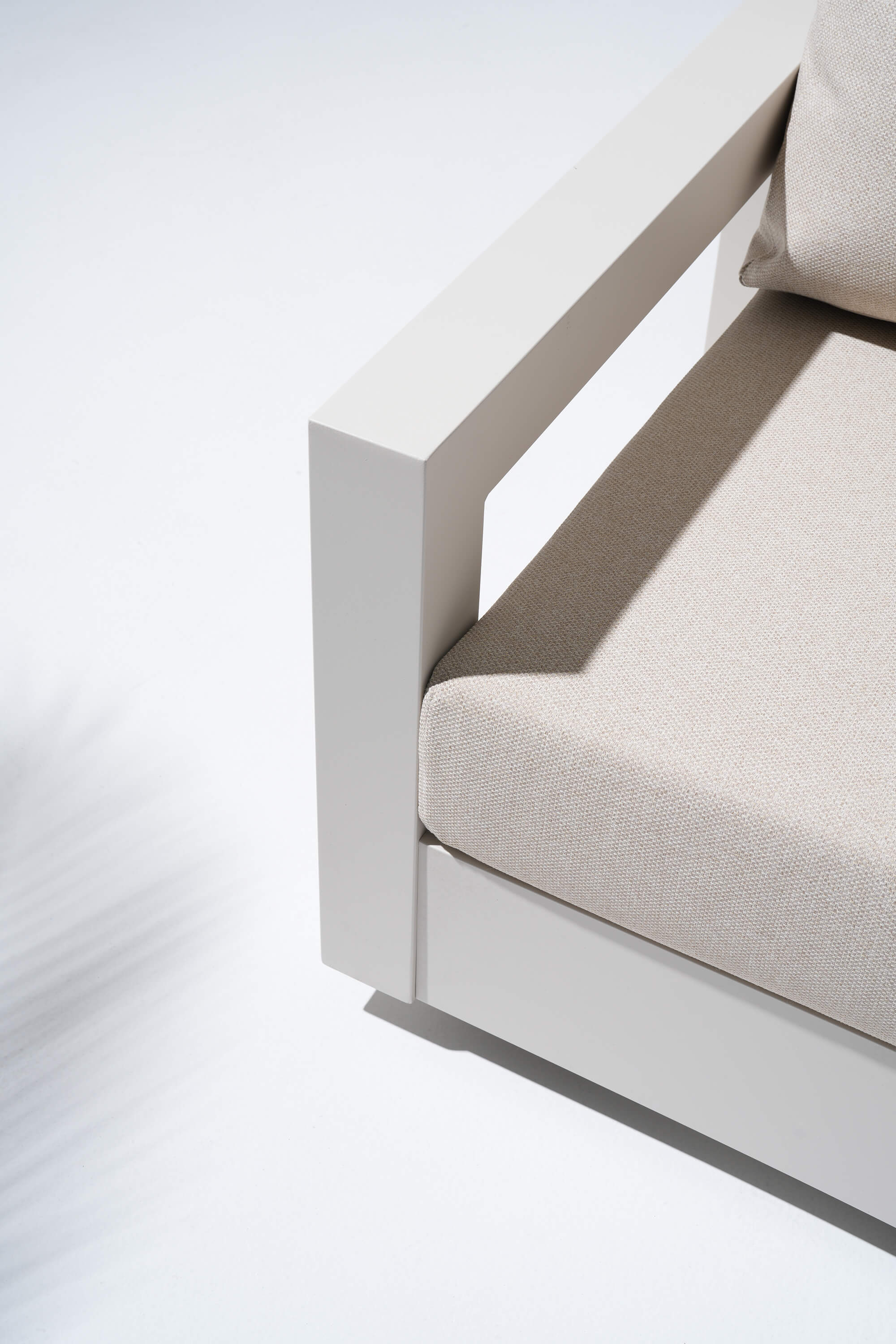 Corner of a modern outdoor sofa with beige cushions
