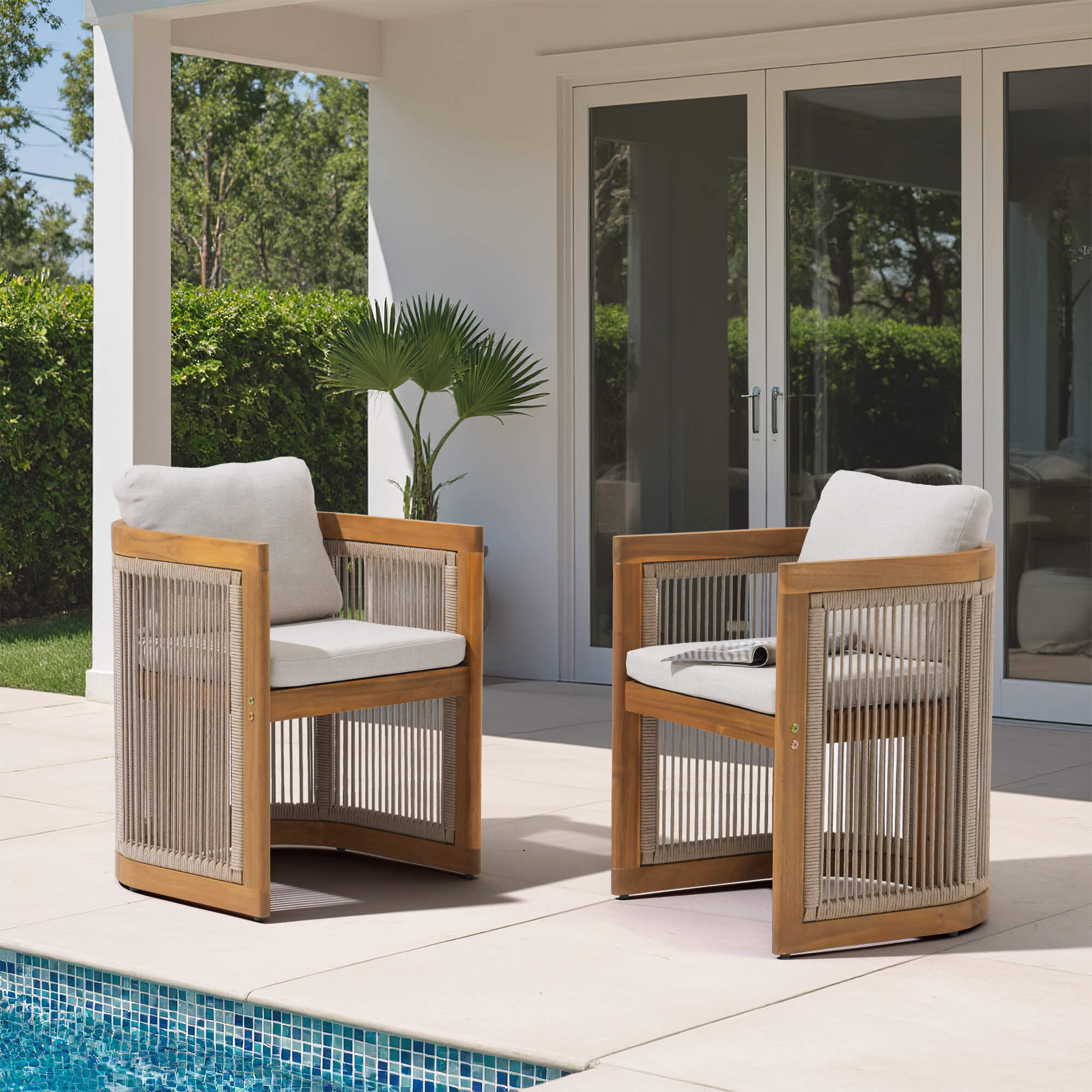 Two rope design wooden outdoor dining chairs with white cushions on a patio by a pool- Jardina Modern Premium Patio Outdoor Furniture