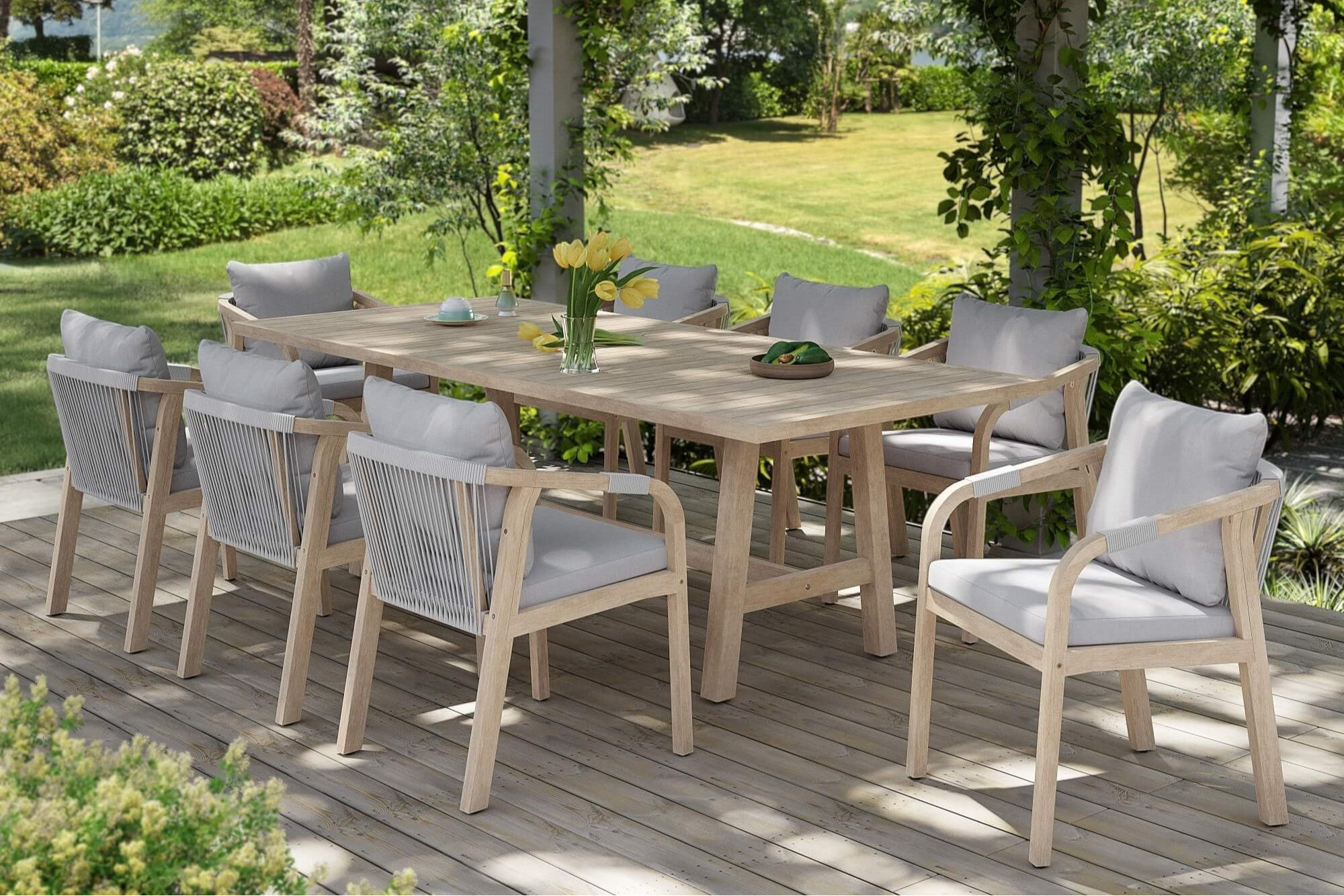 Outdoor dining set with a wooden table and chairs on a wooden deck, surrounded by greenery.