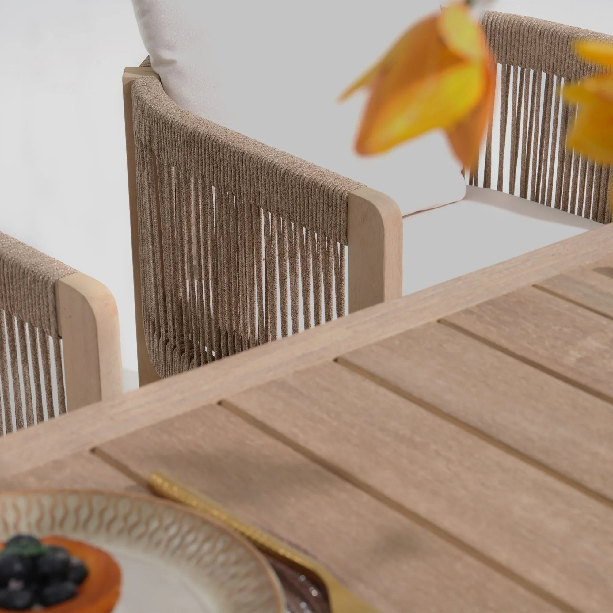 Wooden outdoor table with chairs and a blurred flowerrectnagular wood patio dining tabletop detail - Jardina Modern Premium Outdoor Patio Furniture