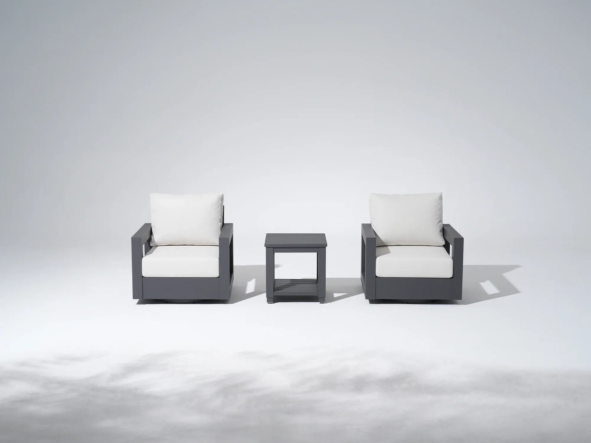 Two modern aluminum swivel chairs with white cushions and a matching side table