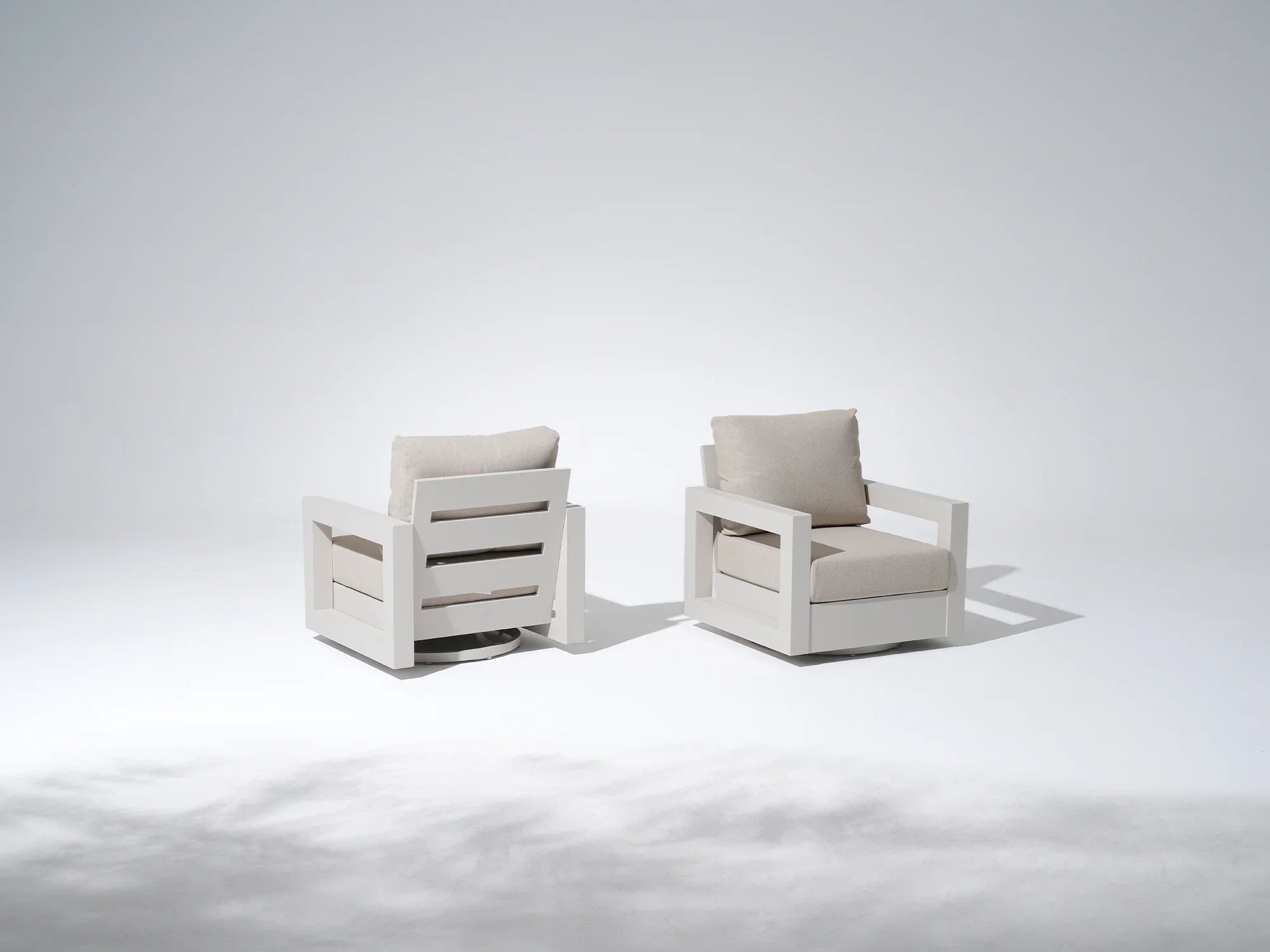 Two modern aluminum bistro chairs with white frames and beige cushions