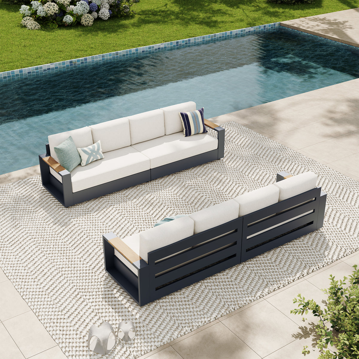 Outdoor patio conversation set with a three-seat sofa and matching loveseat in a modern dark gray frame with off-white cushions, styled on a patterned rug next to a swimming pool. #config_8‑Seat Straight Bundle