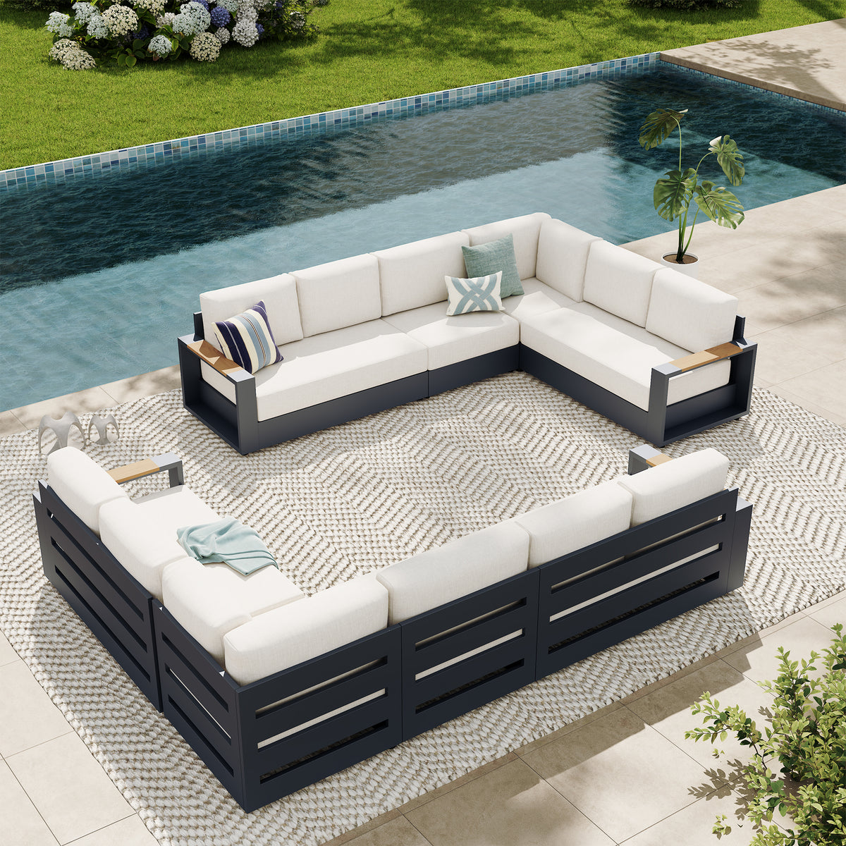 Outdoor sectional patio furniture set with white cushions and dark navy frames, arranged on a patterned rug beside a swimming pool. #config_12-Seat Symmetrical